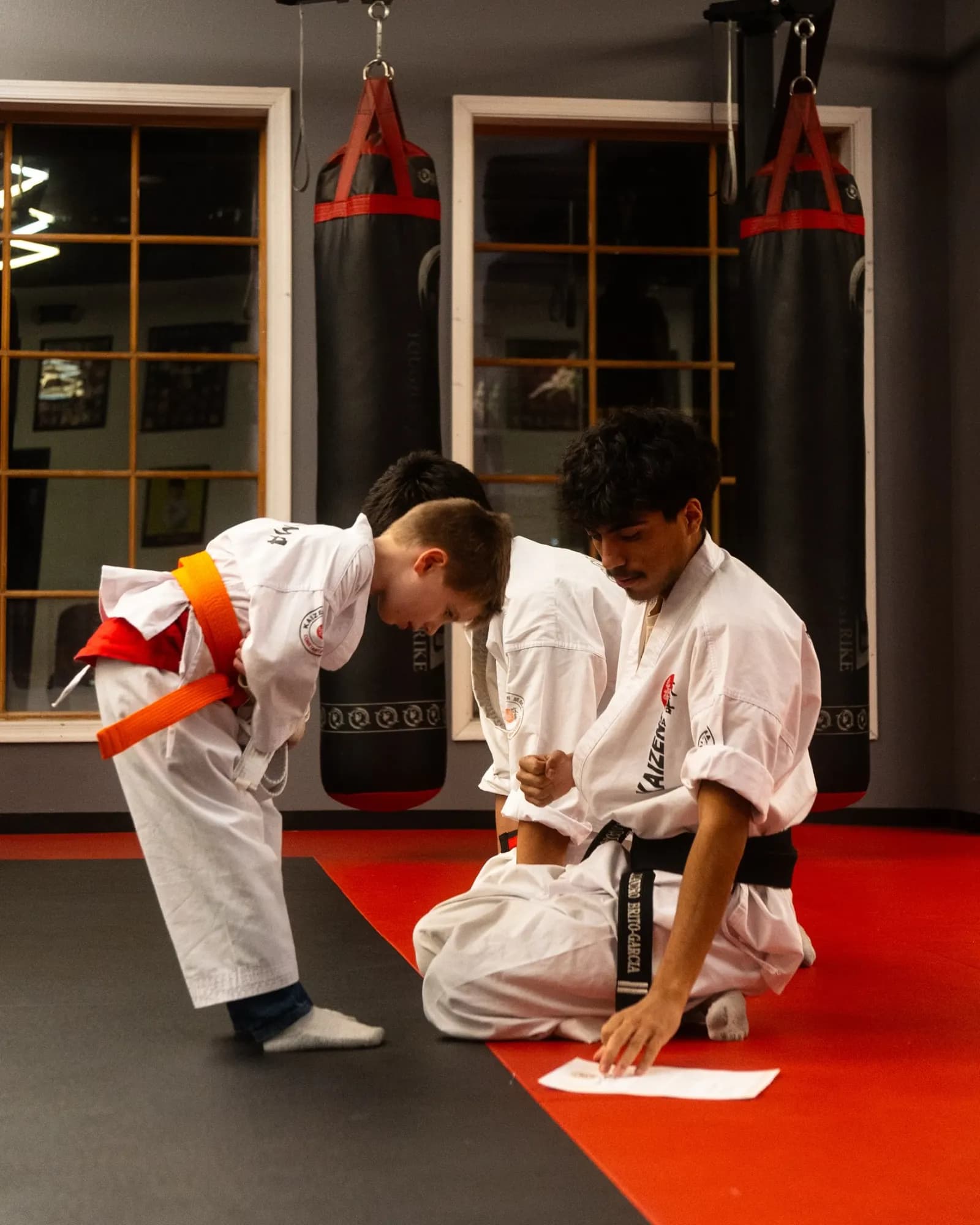 Kaizen MMA instructor teaching a young student with an orange belt