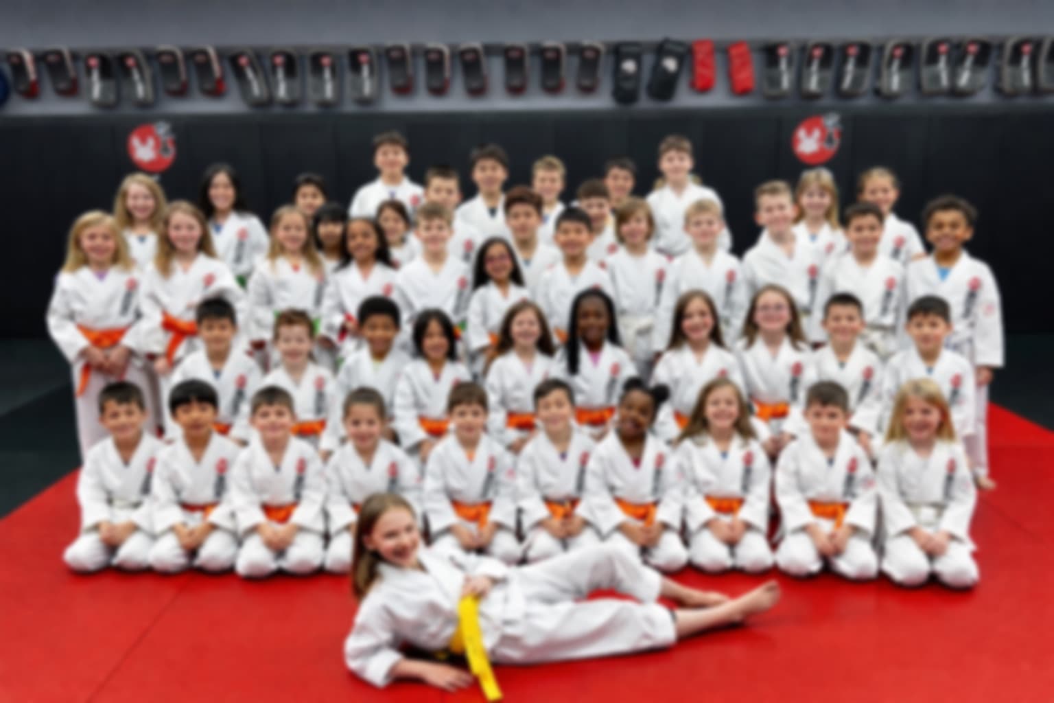The full Young Lions class of older kids in white gis and colored belts at Kaizen MMA South Riding