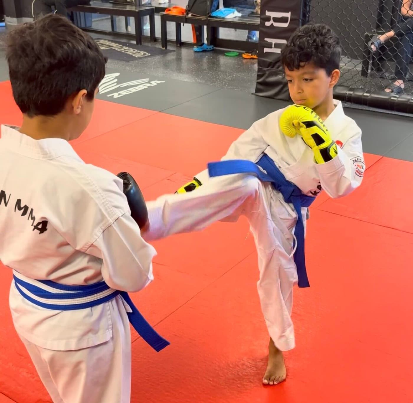 A Young Lions student throwing a front kick into a focus pad during sparring drills at Kaizen MMA South Riding